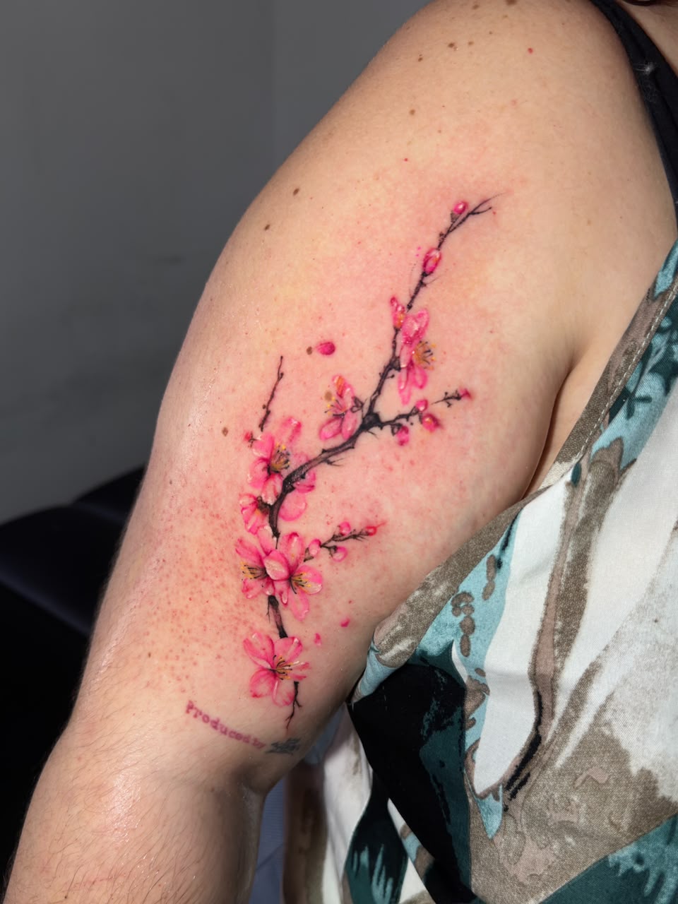 Rama de flores rosadas tatuada sobre el brazo